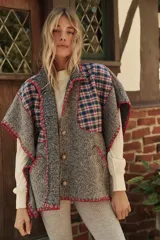 Poncho gris con diseño escocés en azul y rojo, cuello alto, cierre frontal con botones de madera y bordes con terminación crochet en rojo.