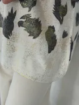 Sweater de punto con cuello en V y mangas largas, de diseño holgado. Presenta un estampado abstracto en tonos verdes con detalles metalizados en color dorado sobre una base de color crema.