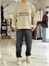 Sweater de punto color beige con cuello redondo, manga larga y diseño estampado en el pecho con las frases "TOP STYLE" y "follow your dreams" en color marrón.