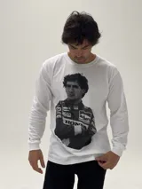 Remera de manga larga color blanco con estampado fotográfico frontal de Ayrton Senna con su traje de piloto de Fórmula 1. Presenta un corte holgado y cuello redondo.