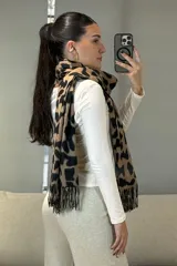Bufanda rectangular con estampado animal print de leopardo en tonos marrones y negros, con terminación de flecos en los extremos.