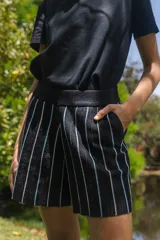 Short amarillo con rayas verticales negras, tejido con lurex y cintura elástica.