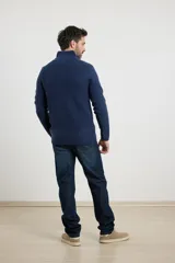 Sweater verde de punto inglés con cuello alto y cierre metálico frontal. Tiene mangas largas y terminaciones en punto canalé.