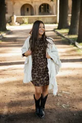 Ruana de lana merino color crudo, con diseño de silueta amplia y caída fluida. Presenta detalles de volados en lino a lo largo de la prenda y terminaciones con flecos en el ruedo.