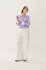 Camisa de popelín con diseño de rayas verticales en tonos blanco y lila, cuello solapa con escote en pico, manga larga y puños anchos contrastantes en color blanco. Cierre frontal con botones metálicos dorados.
