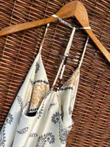 Vestido largo de seda color crudo con estampado de cachemir en negro, musculosa de tirantes finos y espalda semi descubierta.