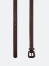 Cinturón fino color beige con hebilla metálica cuadrada.