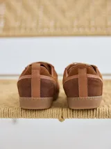 Championes marrones de cuero con cordones intercambiables blancos y rosas, y logo bordado en el lateral.