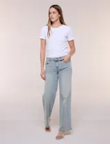 Jean wide leg de tiro medio, color azul claro, confeccionado en denim de algodón con un toque de elastano. Cuenta con cinco bolsillos, presillas para cinturón y cierre frontal con botón. El diseño destaca por su pretina regulable con cruce y broches metálicos.