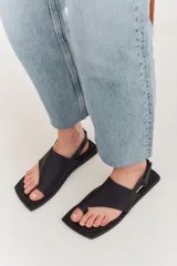 Sandalias de cuero negro con diseño de punta cuadrada, tira ancha sobre el empeine y ajuste con correa en el talón.