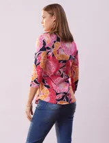 Remera de algodón estampada con flores en tonos celeste, azul y verde, sobre fondo negro. Tiene mangas 3/4 y escote cuadrado.