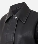 Campera de estilo urbano con corte oversized, confeccionada en poliuretano con base de poliéster. Presenta cuello clásico, cierre frontal con botones a presión, mangas largas y dos bolsillos frontales con tapa. El bajo cuenta con elástico para un mejor ajuste.