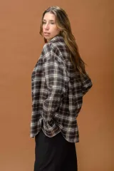 Camisa de corte oversize con diseño a cuadros en tonos marrones, grises y blancos. Presenta cuello clásico, cierre frontal con botones y mangas largas.