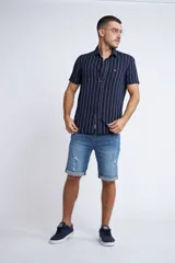 Camisa de manga corta con diseño a rayas verticales en color azul marino y blanco. Presenta cuello clásico, cartera abotonada frontal y logo bordado en el pecho. Posee un corte slim fit.