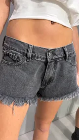 Short de denim de tiro bajo color gris con lavado ácido y bordes desmechados.