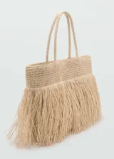 Bolso shopper grande de tejido de fibra natural color beige, con doble asa superior y detalle de flecos en la parte frontal. Cuenta con cierre de botón magnético y bolsillo interior.