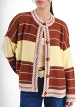 Cardigan tejido de punto jacquard en tonos bordó y rojo con rayas, de corte oversize, cuello redondo y cierre frontal con botones carey. Presenta detalles bordados en contraste y monograma en la espalda.