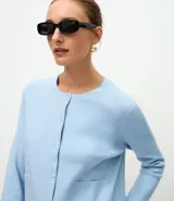 Cardigan de punto color marrón chocolate, con cuello redondo, cierre frontal con botones y mangas largas. Presenta un diseño clásico con acabado canelado en el escote y los puños.