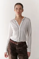 Remera blanca de mangas largas con escote en V y costuras decorativas en negro.
