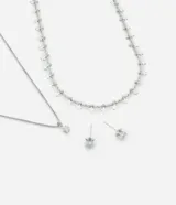 Conjunto de bisutería plateada que incluye un collar con cadena fina y dije de circonia en forma de estrella, un collar tipo choker con cadena de eslabones y múltiples dijes de estrellas, y un par de aros tipo stud con circonias.