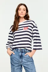 Remera de manga tres cuartos con diseño de rayas horizontales en blanco y azul marino, cuello redondo y silueta amplia. Incluye un pequeño estampado en el pecho con la frase 'have a heart' en forma de corazón.