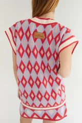 Chaleco tejido de lana con patrón de rombos en tonos lila, rojo y beige, con cuello en V y ribetes en color crema. Diseño oversize.