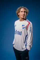 Camiseta de fútbol Umbro del Club Nacional de Football, modelo Home de manga larga. Diseño blanco con detalles en azul y rojo en cuello y puños. Incluye logo de Umbro, escudo del club y sponsors estampados en el frente y mangas.