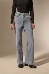 Pantalon de jean de corte recto y tiro medio, con detalle de ojales metálicos a lo largo de la costura lateral externa.