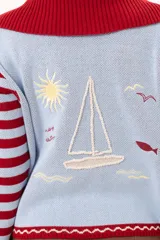 Saco tejido de punto a rayas horizontales en color celeste y rojo, con cuello alto, cierre frontal doble deslizador y puños con diseño en contraste. Presenta un pequeño bordado en el pecho.