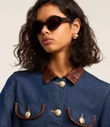 Campera de jean azul con cuello inglés de poliuretano color marrón. Cierre frontal con botones metálicos. Bolsillos de parche en el pecho con detalle de ribete de poliuretano marrón.