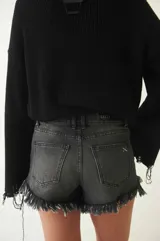 Short de denim azul con lavado medio y detalles de desgaste, tiro alto y ruedo deshilachado.