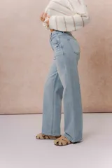 Pantalón de jean tiro alto con calce wide leg, color celeste claro con lavado suave y detalle de desgaste en el bolsillo delantero.