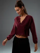 Top corto color bordó, con escote en V, mangas largas abullonadas con puños elásticos y fruncido en la parte delantera.