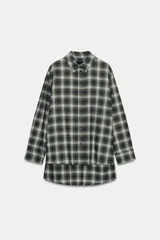 Camisa de corte oversize confeccionada en algodón, con estampado de cuadros en tonos verde, negro y blanco. Presenta cuello solapa, cierre frontal con botones, manga larga con puños y bajo asimétrico.