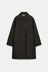 Trench oversize color negro de la colección Zara Woman, confeccionado en hilatura con mezcla de algodón. Presenta cuello solapa, manga larga ajustable con trabillas, bolsillos delanteros y cierre frontal con botones.