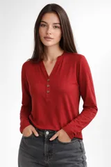 Remera de manga larga confeccionada en viscosa, con cuello en V y cierre frontal parcial con botones.