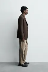 Blazer de corte regular fit confeccionada en tejido de lana italiana. Presenta cuello con solapas de muesca, cierre frontal de un botón, bolsillos de plastrón en el pecho y la cadera, y aberturas en la espalda.