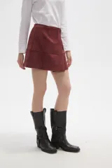 Falda mini de gamuza sintética color bordó, con diseño cruzado y cierre de botón frontal.