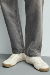 Zapatilla de estilo retro con cordones, confeccionada en una combinación de piezas de cuero sintético negro y detalles en blanco, con suela dentada de goma en tono caramelo.