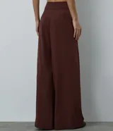 Pantalón de sastrería modelo pantalona, de corte amplio y tiro alto, con cintura lisa y pliegues frontales. Confeccionado en tejido de poliéster con elastano.