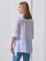 Camisa larga de rayón, con cuello camisero, cierre frontal de botones y mangas con presilla para regular el largo. Presenta un corte holgado con tajos laterales en el ruedo.