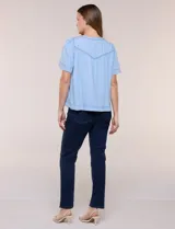 Blusa celeste de lyocell ultraliviano, de estilo romántico y silueta holgada. Presenta escote redondo con abertura en V y botones frontales, canesú fruncido y mangas cortas amplias.