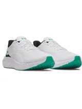 Championes de running Under Armour Ascend, color blanco con detalles en negro y verde. Presentan una entresuela blanca con salpicaduras rosadas y suela verde, confeccionados en malla transpirable con refuerzos en el mediopié.
