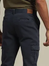 Pantalón cargo de gabardina color azul marino, con bolsillos laterales con fuelle y cierre de botón a presión.