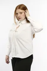 Camisa oversize de manga larga en color blanco, confeccionada en algodón. Presenta cuello clásico, puños abotonados y una abertura central ovalada con jaretas ajustables que permiten fruncir la prenda.
