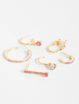 Set de aros dorados con strass rosados, con diferentes diseños: aros tipo argolla con dije colgante, aros tipo argolla con strass en la parte frontal y aros con forma de gota con strass en la parte frontal.