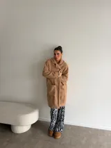 Tapado de textura tipo peluche, color camel, con solapas clásicas, cierre frontal de botones y bolsillos laterales.