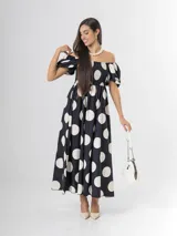 Vestido largo de lunares con escote bote y hombros descubiertos, mangas cortas abullonadas, cuerpo con nido de abeja y falda amplia.