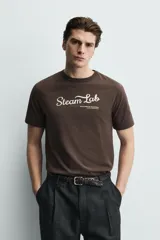 Camiseta regular fit color marrón oscuro, con cuello redondo y manga corta. Presenta un bordado frontal con el texto "Steam Lab" en blanco y una frase más pequeña debajo.