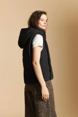 Chaleco acolchado de nylon color negro, con diseño capitoneado, capucha integrada y cierre frontal con tirador metálico.